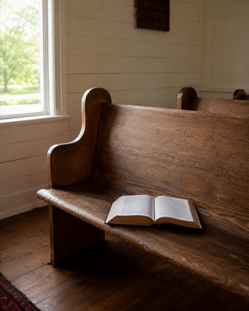 An empty church pew in soft morning light with a worn Bible resting on it, representing God's nearness to the brokenhearted.