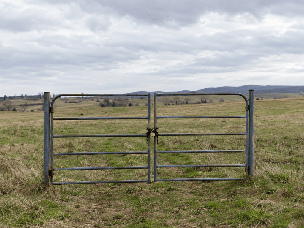 A locked gate standing alone in an open field with no fence attached